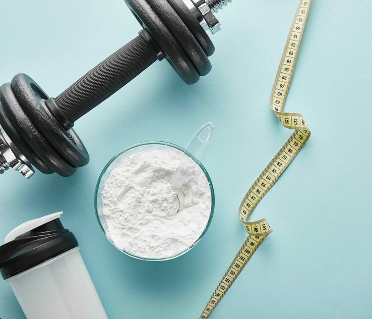 Dumbbells, protein powder, shaker bottle, and measuring tape on a light blue background